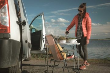Setting-up a lunch on camping furniture in front of a campervan
