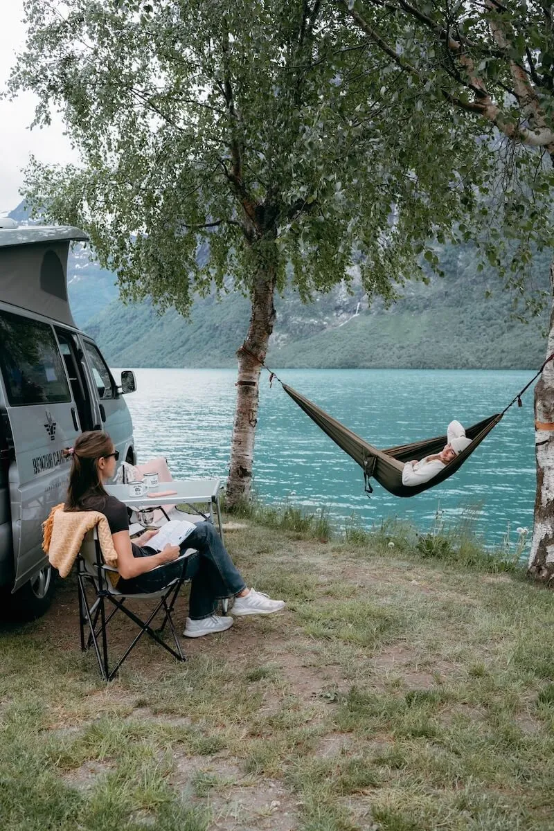 Two girls camping with campervan by Lovatnet lake at campsite