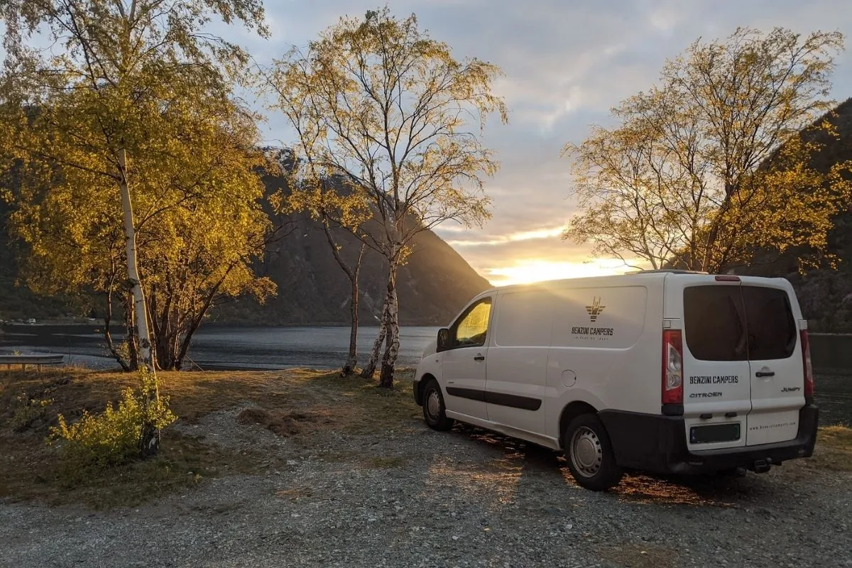 Campervan camping by fjord in Norway at sunset in April