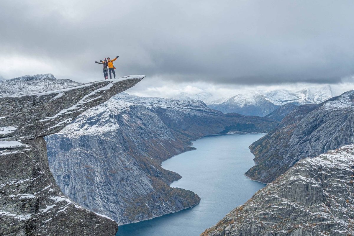 Couple enjoying Trolltunga powdered by snow in April